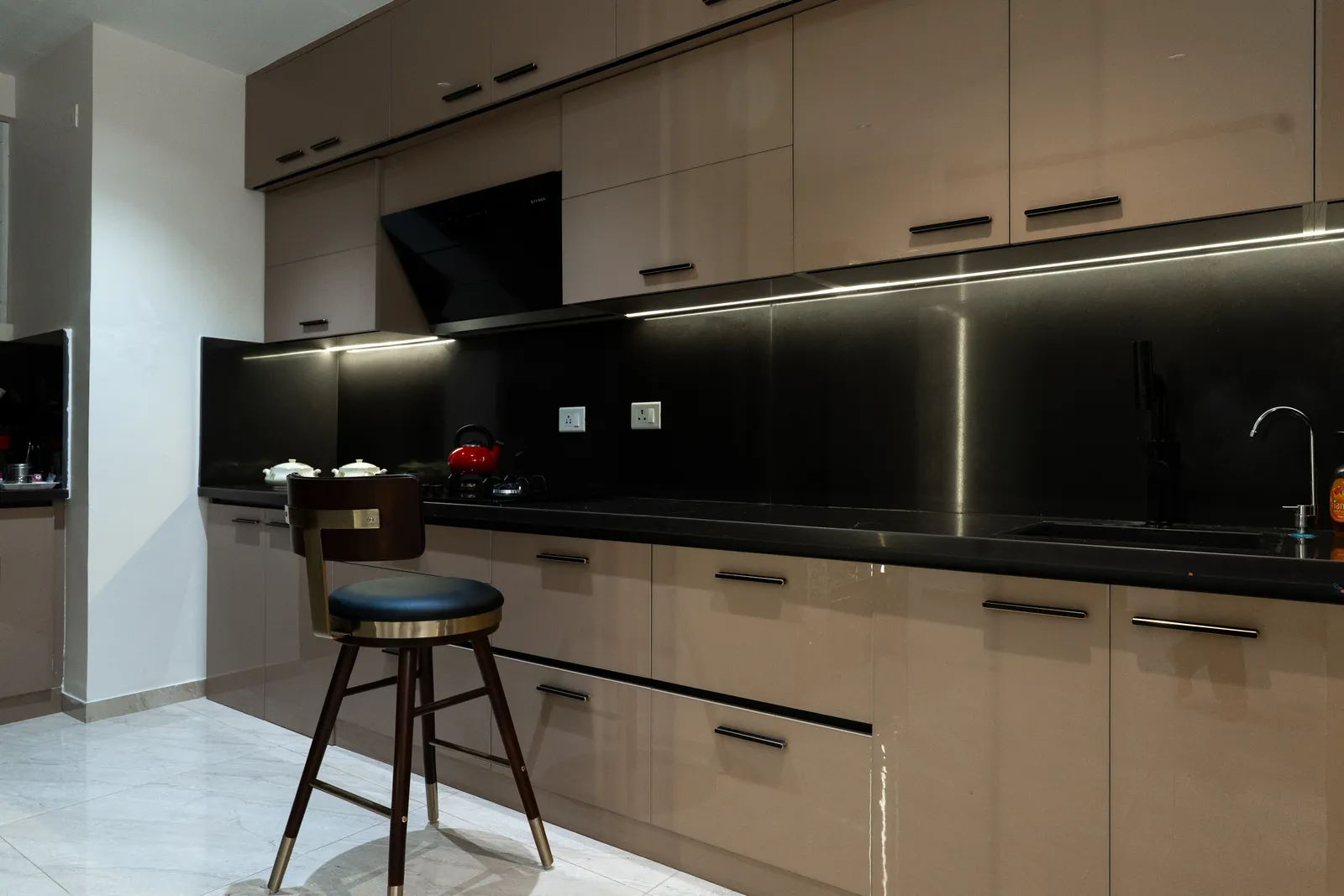 Grey modular kitchen with black backsplash and breakfast stool — Arna's Home